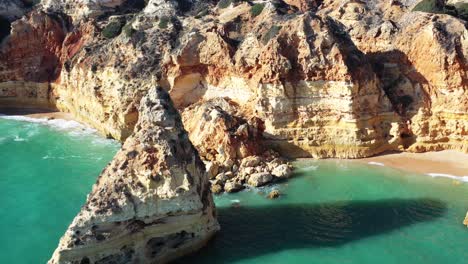 Eroded-rock-formations-in-Marinha-Beach-south-of-Portugal,-Aerial-approach-shot