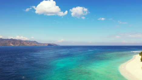 Vivid-colors-of-panoramic-seascape-with-blue-turquoise-sea,-white-sand-of-exotic-beach-under-bright-sky-with-white-clouds-in-Indonesia