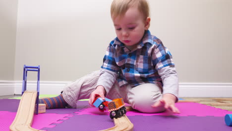 Baby-boy-playing-with-a-wooden-toy-train-set