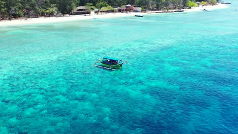 Watercraft-sitting-on-the-surface-of-crystal-clear-blue-waters-on-one-of-Bali's-tropical-beaches