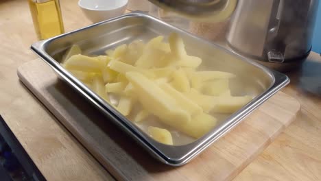Slow-Motion-Slider-Shot-of-Emptying-Parboiled-Potatoes-for-Fries-into-a-Metal-Baking-Tray