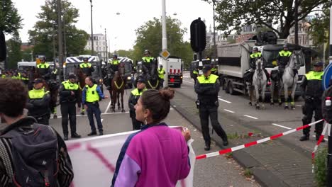 Young-protesters-holding-banners-and-shouting-at-riot-police-horses-blockade-during-extinction-rebellion-in-Amsterdam-about-climate-change
