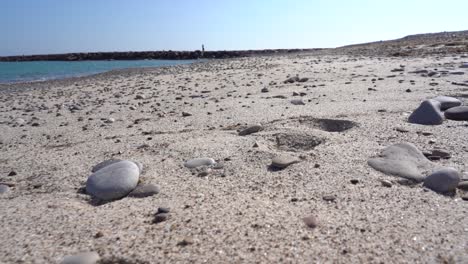 Schuhspuren-Auf-Dem-Strandsand,-Mehrere-Steine,-Schöner-Sonniger-Tag-Und-Ein-Wunderbarer-Blauer-Ozean