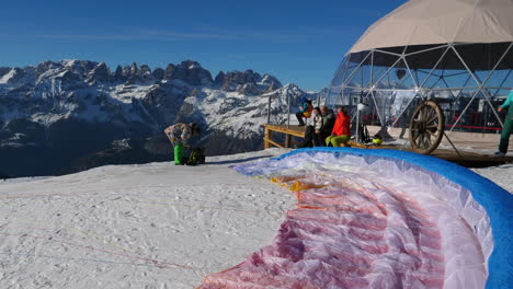 Paragliding-canopy-prepped-on-the-ground-with-a-group-getting-ready-to-fly-in-Trentino,-Italy