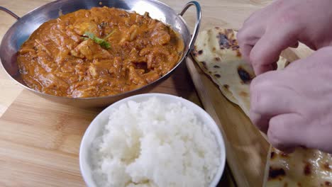 Slider-Aufnahme,-Wie-Man-Ein-Stück-Butter-Naan-Abreißt-Und-Es-In-Ein-Hausgemachtes-Indisches-Curry-In-Einem-Balti-Gericht-Mit-Reis-Taucht