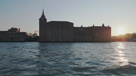 Cruising-Venice,-Italy-cityscape-silhouette-landscape-passing-Hilton-hotel-as-sunset-shines-from-building-edge