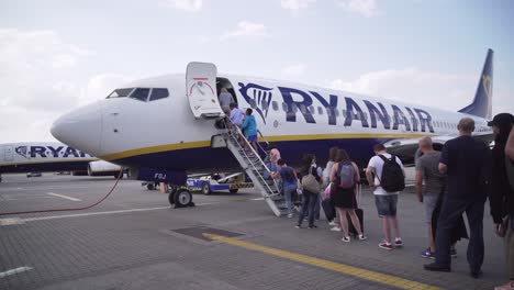 Queue-of-people-boarding-Ryanair-plane-before-takeoff,-side-wide-angle-view