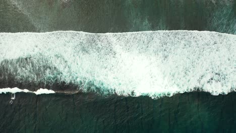 Aerial-of-a-small-white-wave-breaking-and-crashing-in-the-middle-of-the-dark-blue-ocean