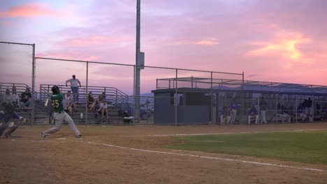 Slow-motion-clip-of-a-batter-hitting-a-home-run-and-sprinting-to-first-base-in-a-minor-league-baseball-game-during-sunset