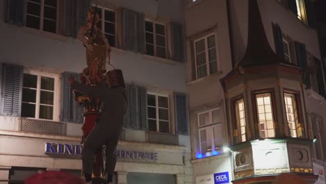 Drunken-person-in-costume-and-bucket-on-head-is-dancing-outdoor-in-city,-holding-on-statue