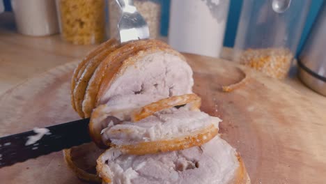 Slow-Motion-Slider-Shot-of-Slicing-a-Roast-Pork-Belly-Joint-with-Crispy-Crackling-on-a-Cutting-Board-in-the-Kitchen
