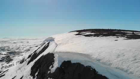 Winter-mountainscape-with-frozen-snowdrift-overhanging-cliff,-revealing-snowdrift