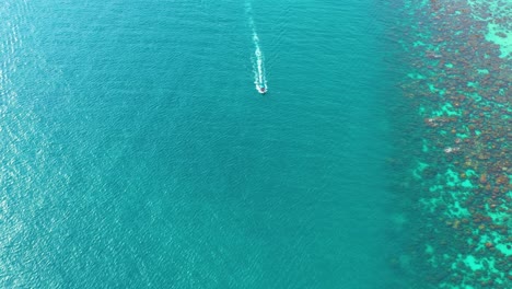 Luftaufnahme-Von-Longtail-Booten,-Die-Auf-Kristallklarem-Wasser-Entlang-Des-Sandstrandes-In-Thailand-Schwimmen