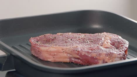 Zeitlupenaufnahme-Des-Hinzufügens-Eines-Ribeye-Steaks-Zu-Einer-Heißen-Grillpfanne