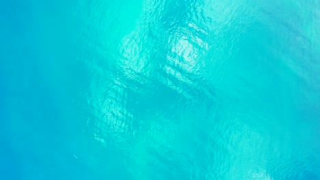 Glassy-sea-texture-with-turquoise-water-reflecting-sunlight,-copy-space-with-abstract-patterns-on-tropical-seascape,-Indonesia