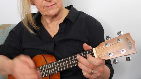 Close-up-view-of-a-woman-playing-ukulele,-tilt-up