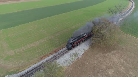 Aerial-over-head-view-of-an-antique-restored-steam-locomotive-traveling-thru-countryside-as-it-is-blowing-black-smoke-and-steam