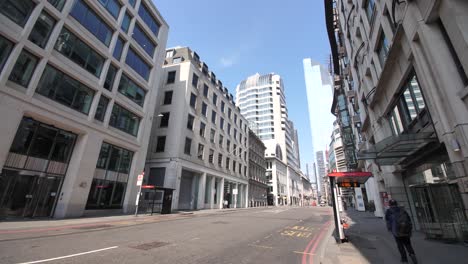 A-single-person-is-walking-alone-down-the-main-road-at-Monument-in-central-London-on-a-sunny-spring-day-during-covid-19-lockdown-and-self-isolation