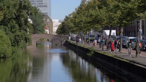 People-walking-next-to-a-canal-in-Hague,-Netherlands