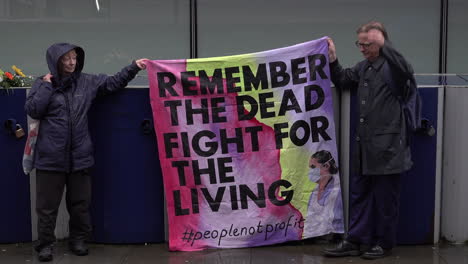 Two-people-hold-a-“Remember-the-dead,-fight-for-the-living”-banner-at-Workers-Memorial-Day-minute-silence-for-healthcare-deaths-outside-The-Royal-London-Hospital-during-the-Coronavirus-outbreak