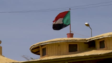 Una-Bandera-Sudanesa-Ondeando-En-El-Viento-En-Cámara-Lenta-Contra-Un-Cielo-Azul