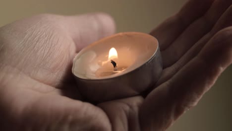 Lit-tea-light-candle-cupped-in-the-palm-of-a-hand