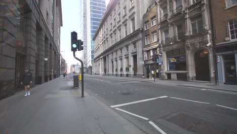 A-single-person-is-out-walking-alone-on-the-busy-Bishopsgate-street-in-central-London-that-is-now-empty-and-quiet-due-to-the-lockdown-of-coronavirus