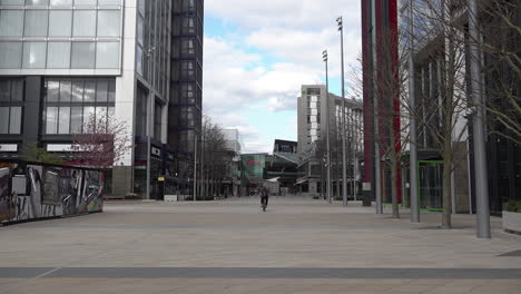 A-group-of-person-cycle-towards-a-near-deserted-Westfield-shopping-centre-at-Stratford-in-East-London-in-what-is-normally-a-busy-shopping-day-during-the-Coronavirus-outbreak