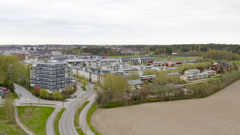 Aerial,-tracking,-drone-shot-of-a-neighborhood,-with-apartment-building-and-row-houses,-in-a-small-town,-cloudy,-spring-day,-in-Viikki,-Finland