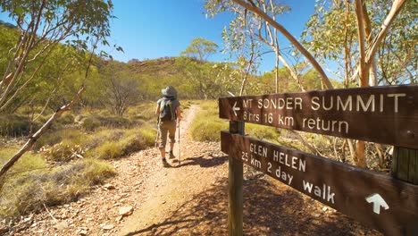 Hiker-walks-past-sign-to-Mt-Sonder-on-Larapinta-Trail,-Central-Australia