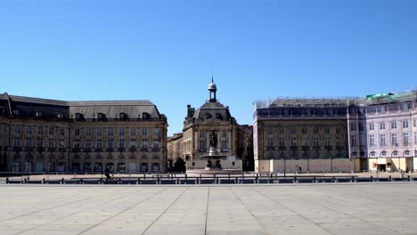 Place-de-la-Bourse-with-bicycles-passing-nearly-empty-square-due-to-the-COVID-19-pandemic,-Stable-handheld-shot