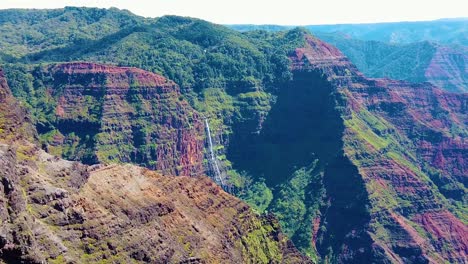 HD-Hawaii-Kauai-slow-motion-wide-shot-of-Waimea-Canyon-with-a-helicopter-in-the-distance-near-a-waterfall-that-flies-away