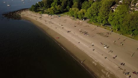 Menschen-Sonnen-Sich-Und-Genießen-Den-Wiedereröffneten-Kitsilano-Beach-Mit-Der-Skyline-Der-Innenstadt-Und-Dem-English-Bay-Beach-In-Vancouver,-Britisch-Kolumbien,-Kanada