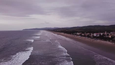 Gente-En-La-Playa-Ondulada-En-Olon,-Ecuador-En-Un-Día-Nublado---Drone-Aéreo