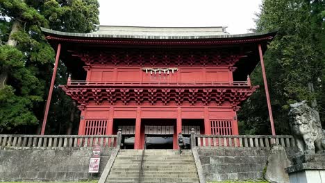 A-japanese-woman-is-walking-up-the-stairs-to-the-red-entrance-gate-of-the-Iwakiyama-Shrine
