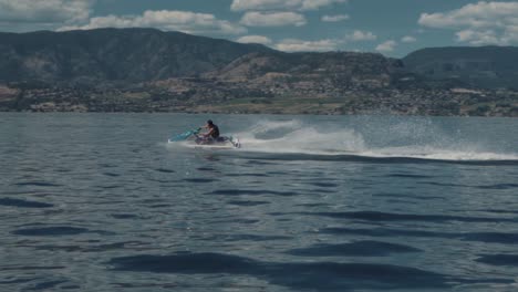 Man-Riding-a-Jet-Ski-in-a-Beautiful-Lake-Setting
