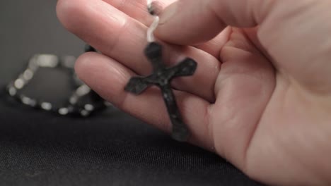 Hand-holding-string-of-rosary-beads-with-crucifix-close-up