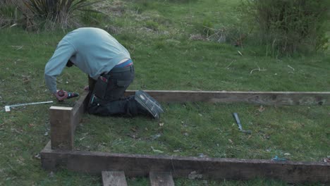 Young-man-building-raised-garden-bed-with-planks