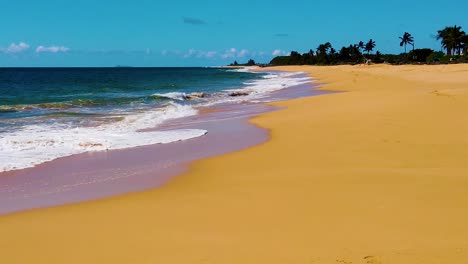 Hd-Hawaii-Kauai-Schwenk-In-Zeitlupe-Von-Rechts-Nach-Links-Vom-Strand-Vorbei-An-Funkelnden-Hintergrundbeleuchteten-Ozeanwellen,-Die-Mit-Einer-Person,-Die-Am-Rand-Der-Wellen-In-Der-Ferne-Mit-Teilweise-Bewölktem-Himmel-Steht,-An-Den-Strand-Krachen