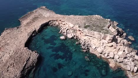 Aerial-Orbit-Shot-of-a-Secret-Moon-shaped-Island-in-the-North-of-Ibiza-On-Turquoise-Waters