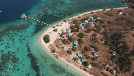 Luftdrohnenaufnahme-Einer-Kleinen-Insel,-Umgeben-Von-Türkisfarbenem-Ozeanwasser-Mit-Korallenriffen-Und-Einigen-Booten-Im-Hintergrund
