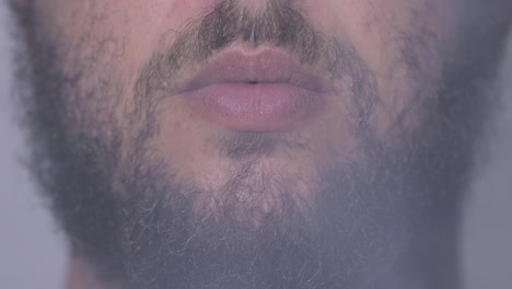 Closeup-on-bearded-man-mouth-smoking-vape-and-releasing-smoke
