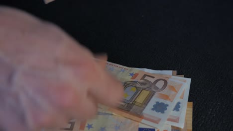 Eine-Nahaufnahme-Männlicher-Hände,-Die-Euro-Banknoten-Auf-Einer-Schwarzen-Oberfläche-Zählen
