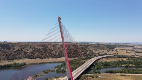 Drone-shot-of-red-modern-cable-strayed-bridge-over-river-in-Talavera-de-la-Reina,-Spain