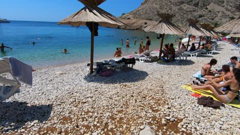 Reveal-crowd-of-people-at-paradisiac-beaches-of-Krk-Island,-Croatia