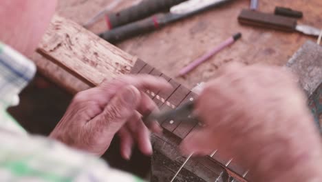 A-Luthier's-Hands-Installing-Frets-On-The-Fretboard-Of-A-Guitar---close-up