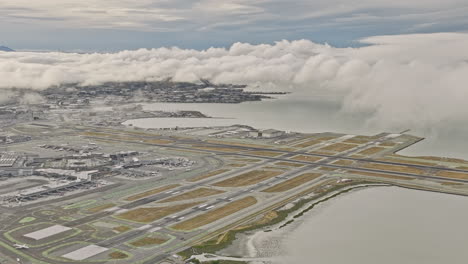 Burlingame-California-Aerial-v7-high-flyover-ingold-milldale-and-millbrae-neighborhoods,-zoom-in-and-out-into-sfo-airport-by-the-bay-with-thick-clouds-in-the-sky---Shot-with-Mavic-3-Cine---June-2022