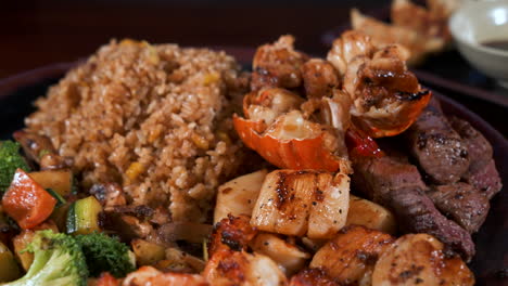 Surf-and-turf-hibachi-plate,-mixed-proteins-lobster-steak-scallops-shrimp-fried-rice-mixed-vegetables,-slider-close-up-4K