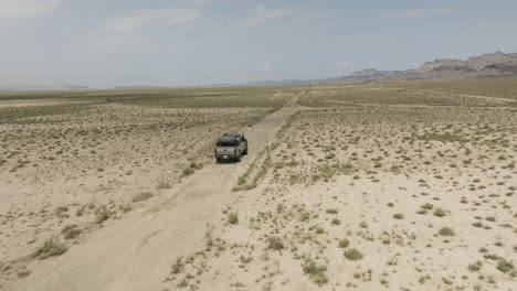 Jeep-driving-on-dirt-road-in-arid-steppe-plain-in-Vashlovani,-Georgia