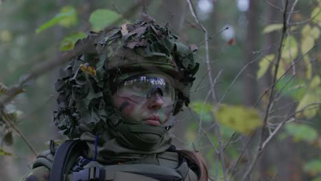 Female-soldier-in-camouflage-looking-listening-in-forest,-closeup,-handheld